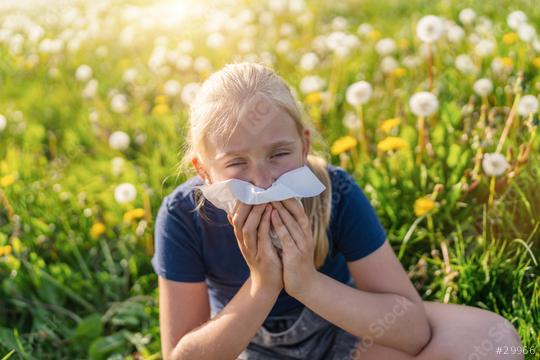 young girl sits in a field of dandelions, holding a handkerchief to her nose, showing signs of allergies. The bright sunlight and blooming flowers highlight the springtime setting  : Stock Photo or Stock Video Download rcfotostock photos, images and assets rcfotostock | RC Photo Stock.: