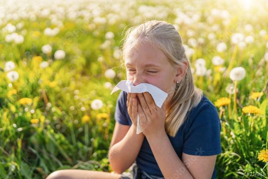 young girl sits in a field of dandelions, holding a handkerchief to her nose with a sneezing expression, indicating allergy symptoms. The bright sunlight highlights the springtime setting  : Stock Photo or Stock Video Download rcfotostock photos, images and assets rcfotostock | RC Photo Stock.: