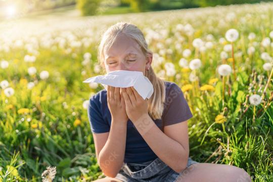 young girl sitting in a field of dandelions, sneezing into a handkerchief, displaying signs of allergy to pollen and grasses. The bright sunlight emphasizes the springtime atmosphere.  : Stock Photo or Stock Video Download rcfotostock photos, images and assets rcfotostock | RC Photo Stock.: