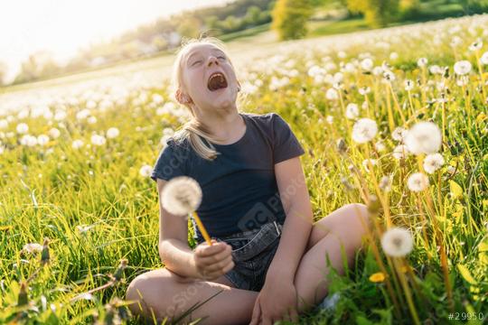 young girl sitting in a sunny field full of dandelions, holding one in her hand and laughing joyfully with her head tilted back. The sun is shining brightly, capturing the essence of a warm spring day  : Stock Photo or Stock Video Download rcfotostock photos, images and assets rcfotostock | RC Photo Stock.: