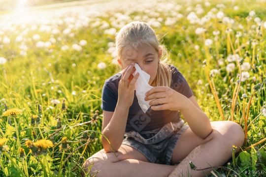 young girl sitting in a sunny field full of dandelions, holding a handkerchief to her face, showing signs of allergy to pollen and grasses in spring. The sun is shining brightly on spring day  : Stock Photo or Stock Video Download rcfotostock photos, images and assets rcfotostock | RC Photo Stock.: