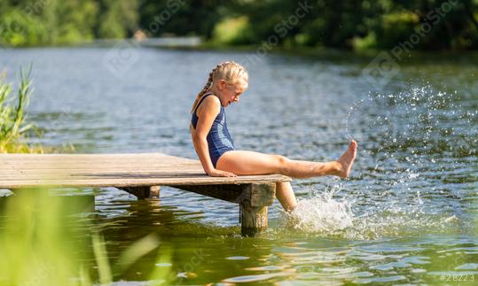 Young girl splashing water with her foot while sitting on a wooden dock by a lake on a sunny day  : Stock Photo or Stock Video Download rcfotostock photos, images and assets rcfotostock | RC Photo Stock.: