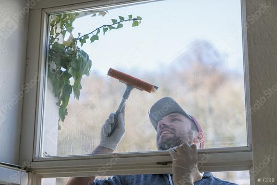 young man is using a rag and squeegee while cleaning windows. professional window cleaner  : Stock Photo or Stock Video Download rcfotostock photos, images and assets rcfotostock | RC Photo Stock.: