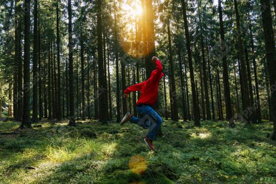 Young man jumps in the green forrest with red jacket and enjoys nature  : Stock Photo or Stock Video Download rcfotostock photos, images and assets rcfotostock | RC Photo Stock.: