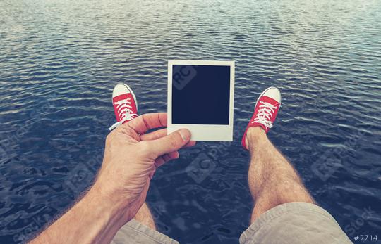 Young man with Picture Frame in his hand sitting above the ocean, Point Of View Shot.  : Stock Photo or Stock Video Download rcfotostock photos, images and assets rcfotostock | RC-Photo-Stock.: