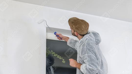 young painter working with paint roller to paint the corner of a room window with white color  : Stock Photo or Stock Video Download rcfotostock photos, images and assets rcfotostock | RC Photo Stock.: