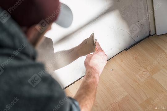 young scratch with a spatula on a wall of a room. do it yourself concept image  : Stock Photo or Stock Video Download rcfotostock photos, images and assets rcfotostock | RC Photo Stock.:
