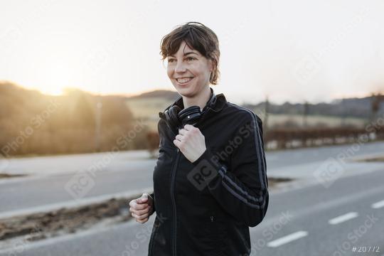 Young woman is jogging outside on the street. The athletic person is full of motivation and happy.  : Stock Photo or Stock Video Download rcfotostock photos, images and assets rcfotostock | RC Photo Stock.:
