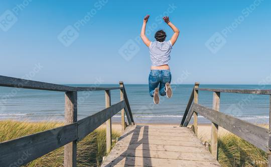 Young Woman Jumps on Beach over a wooden path to the Baltic sea on a summer day  : Stock Photo or Stock Video Download rcfotostock photos, images and assets rcfotostock | RC Photo Stock.: